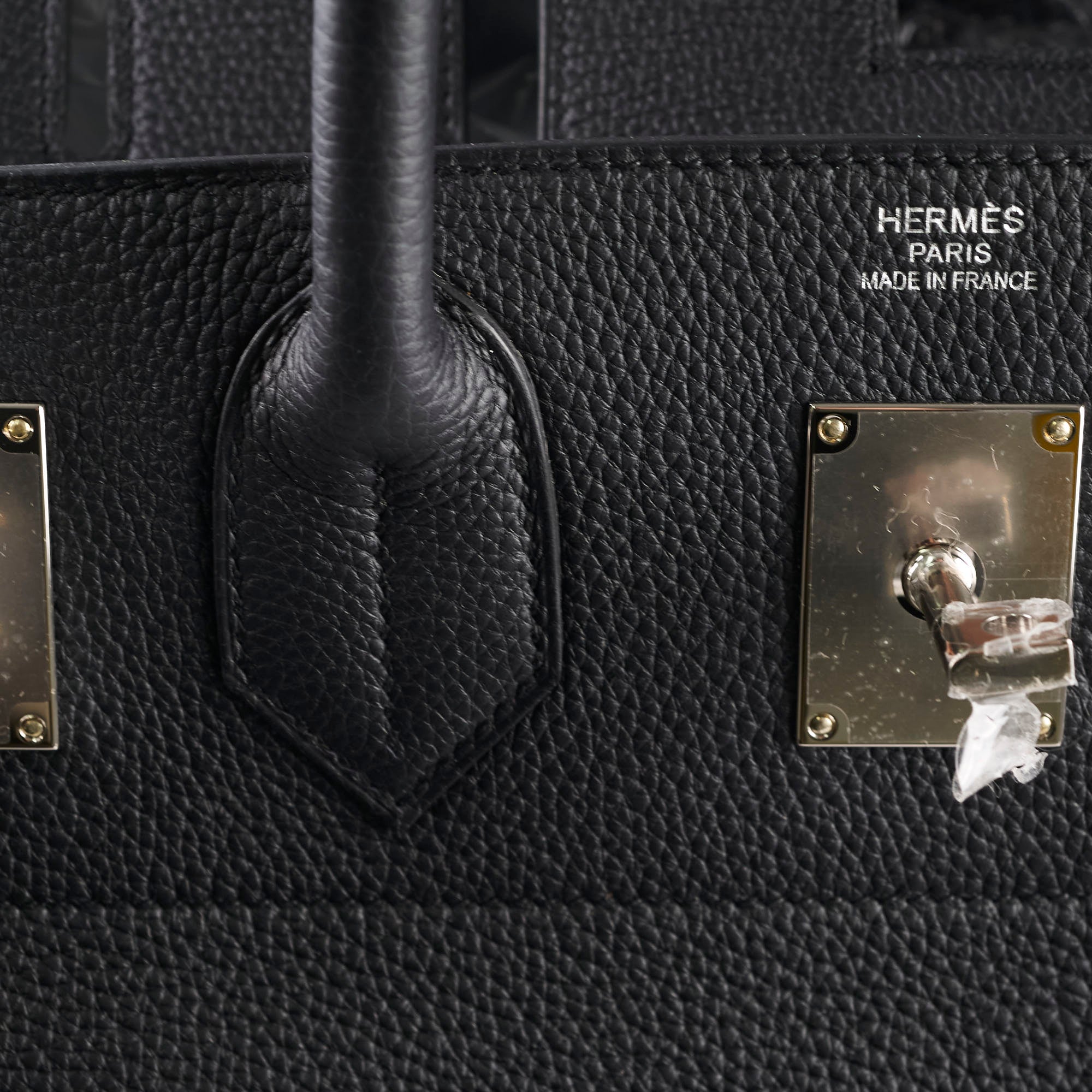Close-up of a black Hermès bag with gold hardware.