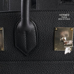 Close-up of a black Hermès bag with gold hardware.